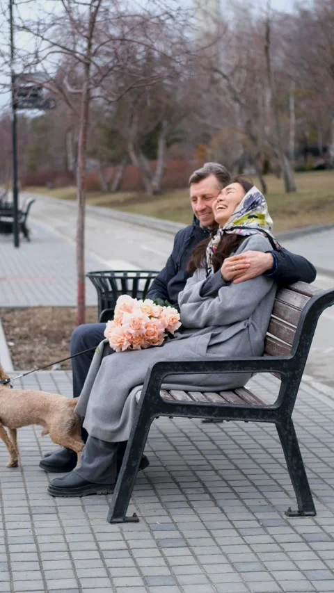 Couple relaxing on a bench during a walk in the park. A loving couple walks Stock Footage 312351150