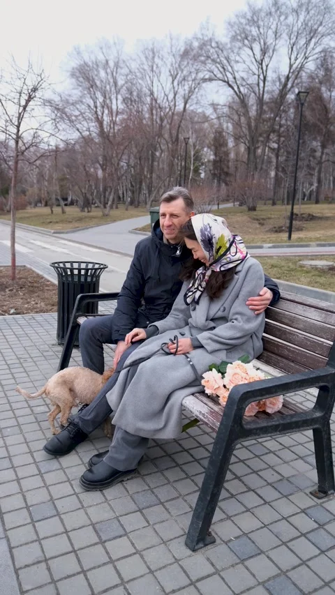 Couple relaxing on a bench during a walk in the park. A loving couple walks Stock-Footage 312370439