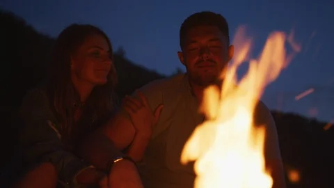 Couple relaxing by a campfire Stock Footage 99968602