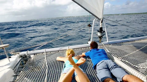 Couple relaxing on catamaran net looking at the sea Stock Footage