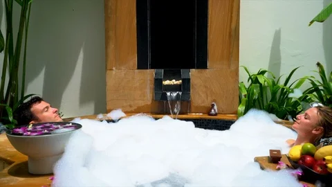 Couple relaxing in huge bubble bath Stockbeeldmateriaal 90839555