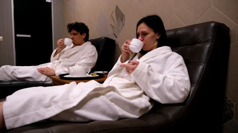 Couple relaxing resting lying in soft comfort leather armchairs in modern sauna. Stock Footage 311887111