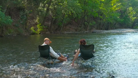 Couple relaxing in river with camping chairs Stock Footage 345400151