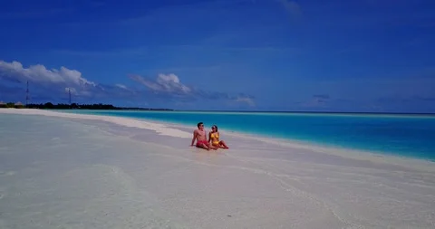 Couple relaxing off the shore of tiny tropical island on yellow Stock Footage 118437171
