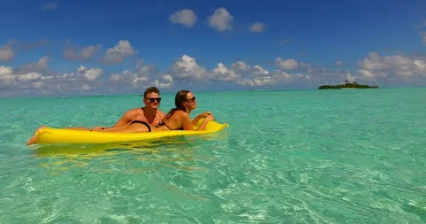 Couple relaxing off the shore of tiny tropical island on yellow Stock Footage 118437425