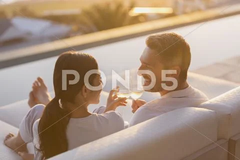 Couple relaxing toasting white wine glasses on chaise lounge on luxury patio Stock Photos