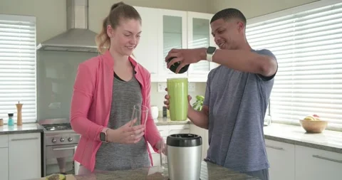 Couple removing green blender lid and pouring thick green smoothie into tall Video stock 345123761