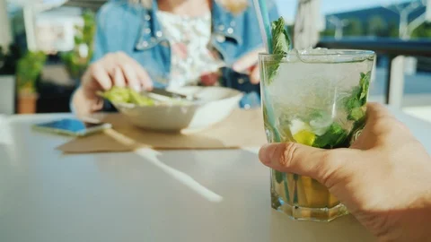A couple is resting in a cafe. First person view - a man holding a glass with a Stock Footage 90249621
