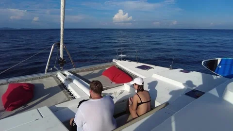 A couple is resting in the rest area on the bow of a sailing catamaran Stock Footage 220345672