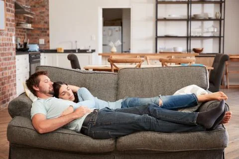 Couple Resting On Sofa In Open Plan Lounge Fotos de archivo