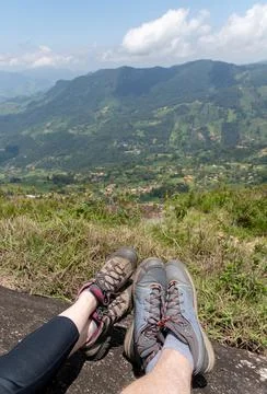 Couple resting in the top of a mountain showing their feet in front of a natu Stock Photos