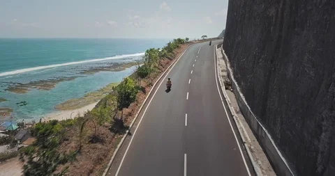 Couple rides on a road between mountain and ocean Video stock 124650169