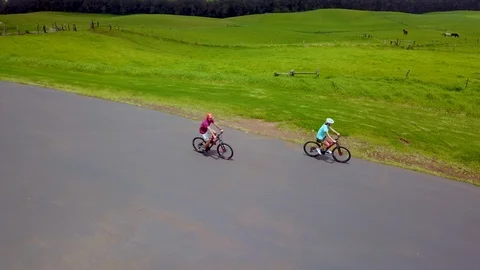 Couple Riding Bikes Past Fields at a Ranch in Hawaii - Aerial Drone Stock-Footage 92886946
