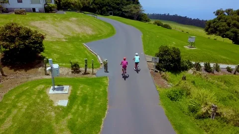 Couple Riding Bikes Past Fields at a Ranch in Hawaii - Aerial Drone Video stock 92887361