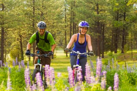 Couple riding mountain bikes in meadow Stock Photos