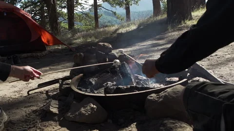A couple roasting marshmallows over a campfire in the mountains Stock Footage 138475095