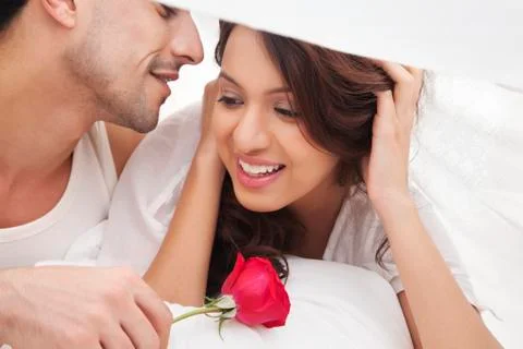 Couple romancing in bed Stock Photos
