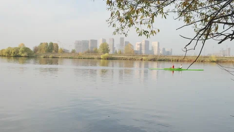 Couple rowing on the tranquil river against modern buildings, slow motion video Stock Footage 143140105