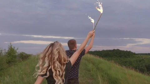 Couple run at sunset with sparkle in hands kissing Stock Footage 76863406