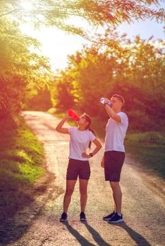 Couple of runners resting while training and drinking water Stock Photos