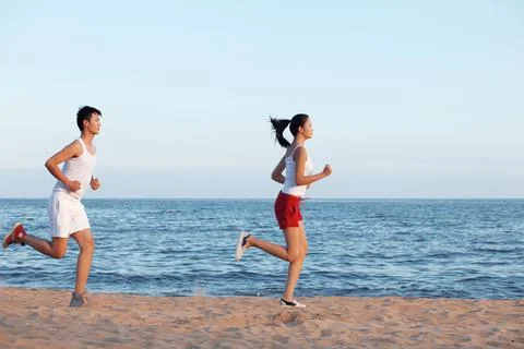 Couple running on beach Stock Photos