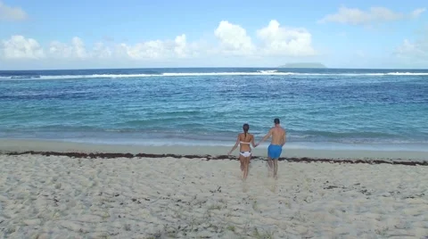 Couple running on the beach into the water Vidéo 58892998