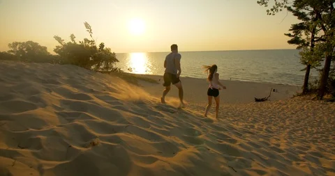 Couple Running Down Dunes at Sunset Stock Footage 98881230