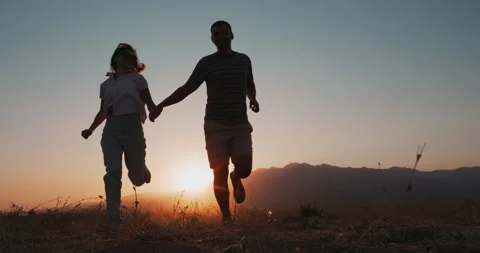 Couple running in a field at sunset, holding hands Stock Footage 229897299