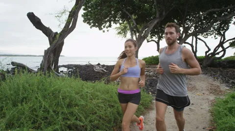 Couple running on forest trail path by beach - runners jogging exercising Video stock 61745994
