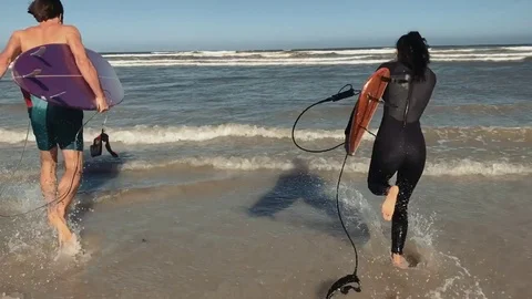 Couple running into ocean with surfboards Stock Footage 76520476