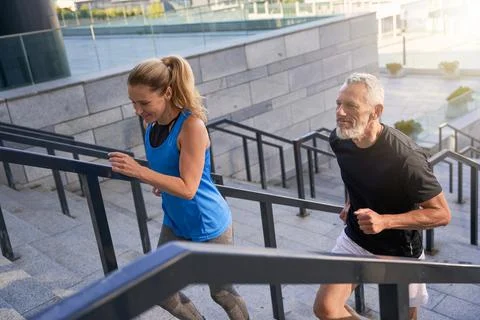 Couple running up the stairs in city while exercising together outdoors. Active Stock Photos