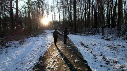 A couple runs down a snow covered path in Maryland Stock Footage 169038193