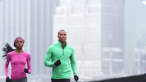 A couple runs towards the camera in slow motion with the city behind them Stock Footage 45078229