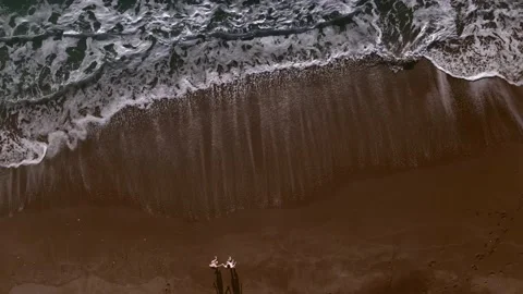 Couple on a sandy beach by the sea. Two are standing by the sea. Top view drone Stock Footage 233143991