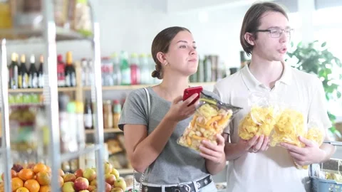 Couple scans the QR code on crispy snacks and potato chips , reads information Stock Footage 312627110