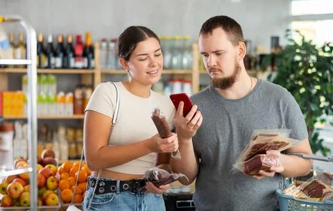 Couple scans the QR code of meat products on their phone Stock Photos