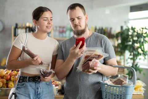 Couple scans the QR code of meat products on their phone Foto stock