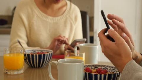 Couple scrolling through smart phone at breakfast table Video stock 99684083