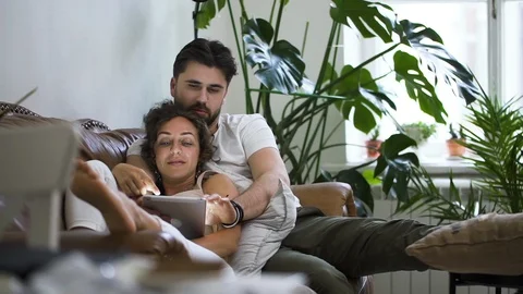 Couple searching information browsing internet tablet while lying in living room Stock Footage 130169921