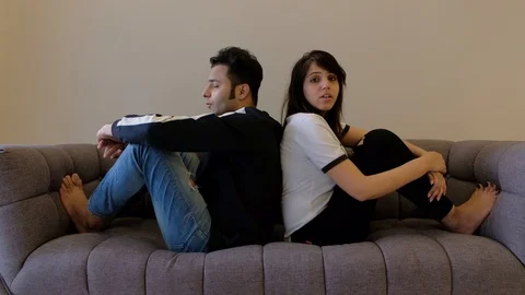 Couple seated back to back turn around and look at camera point fingers to disci Stock Footage 100632122