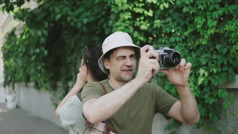 Couple senior tourists stand back to back, one taking photos with a vintage Stock Footage 301106947