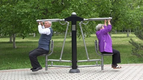 Couple of senior training at gym machine in park, healthy lifestyle, gray hair Stock Footage 82989672