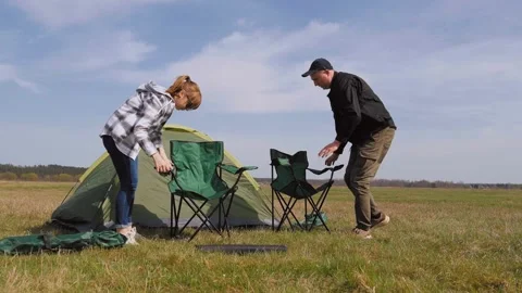 Couple setting up folding chairs at campsite Vidéo 319788250
