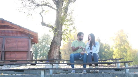 Couple sharing earphones while listening to music on smartphone Stock Footage 59555121