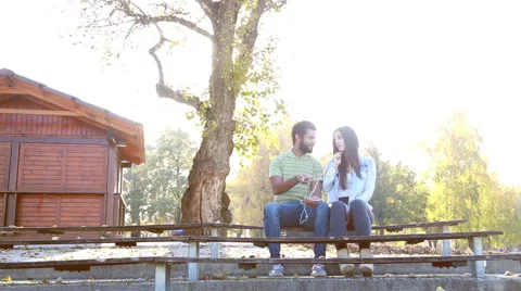 Couple sharing earphones while listening to music on smartphone Stock Footage 59555135