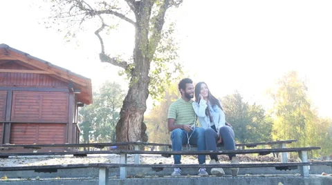 Couple sharing earphones while listening to music on smartphone Stock Footage 59555137