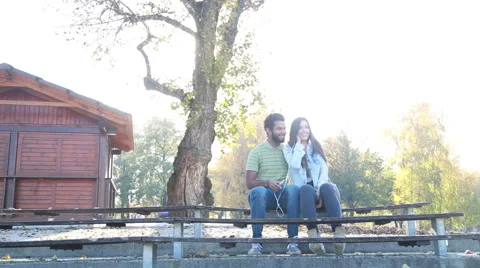 Couple sharing earphones while listening to music on smartphone Stock Footage 59555142