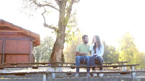 Couple sharing earphones while listening to music on smartphone Stock Footage 59555168