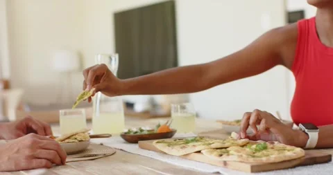 Couple sharing flatbread at dining table to share meal, woman in red top Stock Footage 339559072