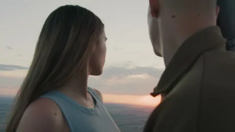 Couple sharing intimate gaze under drifting paraglider at sunset Stock Footage 317169157